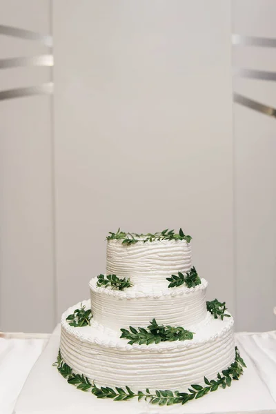 Luxury wedding tiered white cake decorated with flowers, photo at night on the background of lights
