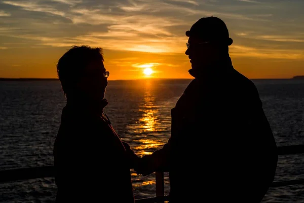 Couple at the railing of a ship in front of the sunset on the North Atlantic coast of Thurso, Scotland, United Kingdom, Europe