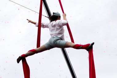 Ona bacaklar açık geniş genç acrobat asılı.
