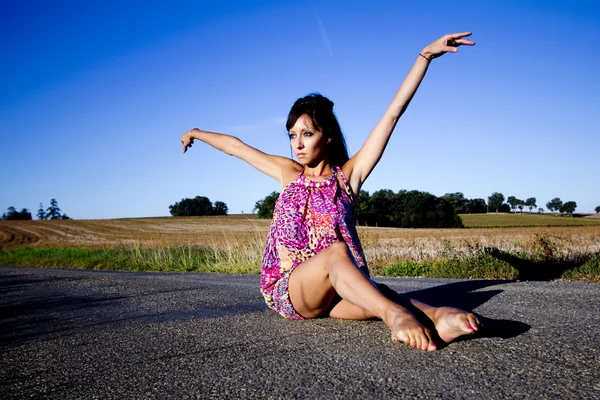 Bailarina elegante sentada sobre el asfalto . — Foto de Stock