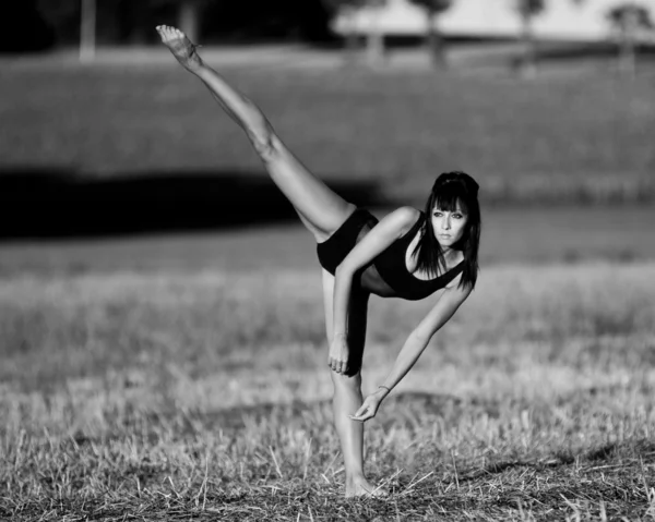 Barefoot danser balanceert op een been in een veld. — Stockfoto