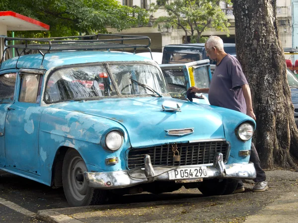 Alter mann beim putzen seines alten amerikanischen blauen autos in havana. — Stockfoto