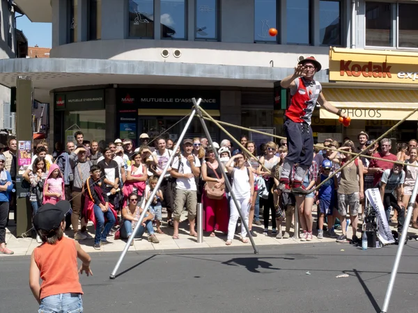 Kind wirft einem akrobatischen Jongleur einen roten Ball zu. — Stockfoto