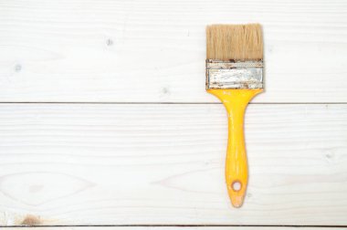 Beyaz ahşap sırtüstü sarı saplı kullanılmış boya fırçası.