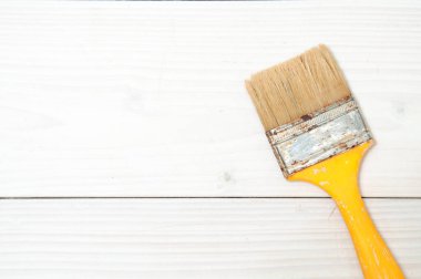 Beyaz ahşap sırtüstü sarı saplı kullanılmış boya fırçası.