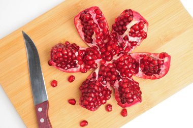 Kesme tahtasındaki dilimlenmiş nar kamaları izole edilmiş beyaz arka grubunda bıçakla.