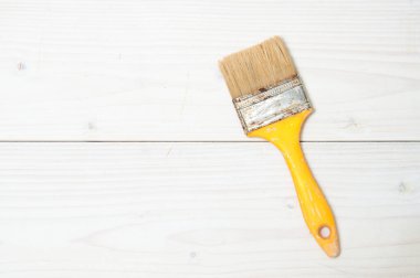 Beyaz ahşap sırtüstü sarı saplı kullanılmış boya fırçası.