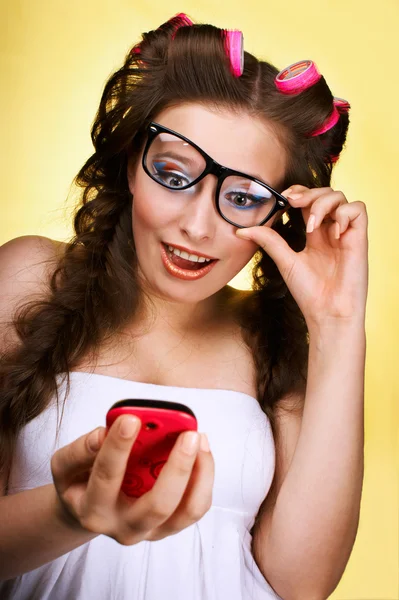 Giovane bella ragazza con gli occhiali e un telefono su uno schienale giallogr — Foto Stock