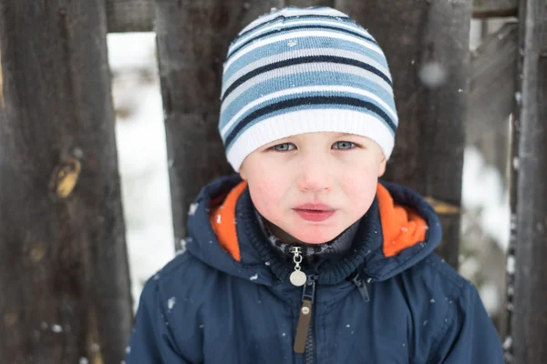 Porträtt av en liten pojke i ett staket i trä på vintern — Stockfoto