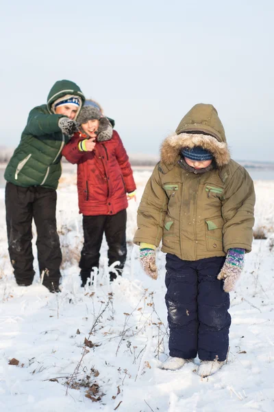 Kinderen bespotten kind buiten in de winter op de straat — Stockfoto