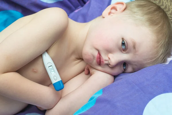 Niño Grip paciente acostado en la cama con un termómetro — Foto de Stock