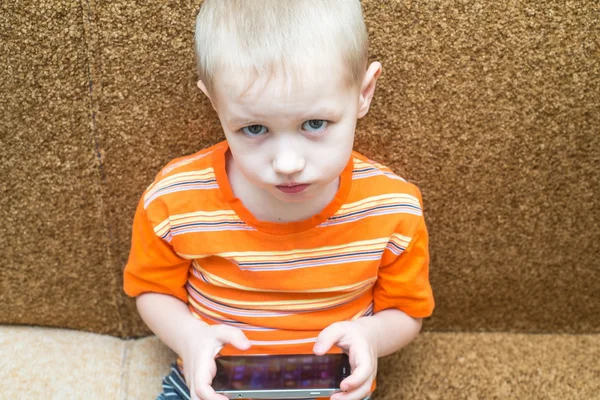 Malý chlapec sedící na gauči v smartphone — Stock fotografie