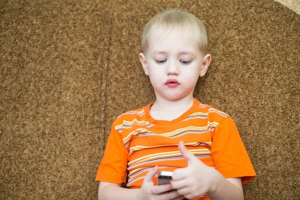 Petit garçon assis sur le canapé jouant dans le smartphone — Photo