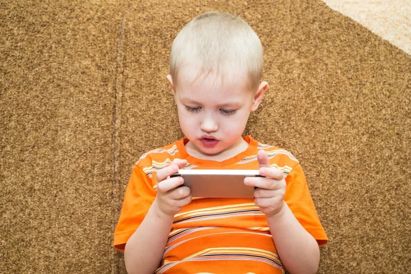 Malý chlapec sedící na gauči v smartphone — Stock fotografie