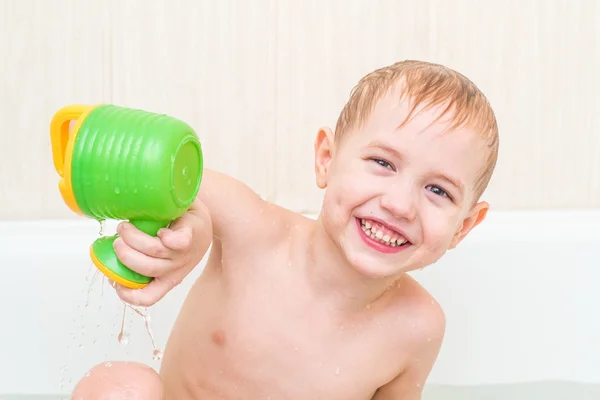 El hermoso niño se baña en un baño azul con un juguete —  Fotos de Stock