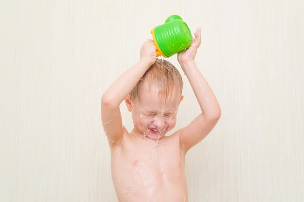 Liten pojke i badrummet på en vit bakgrund Häll över huvudet med en flaska vatten — Stockfoto