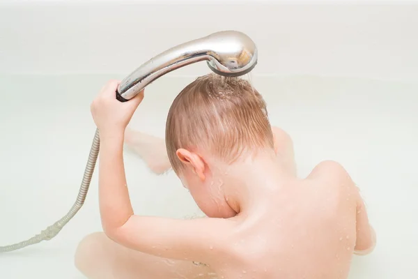 En søt gutt på fire år bader i en dusj. – stockfoto