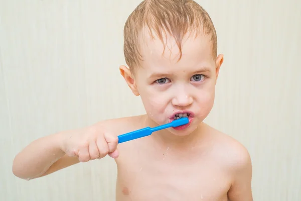 Blonde beautiful boy brushing his teeth in the bathroom — Stock Photo, Image