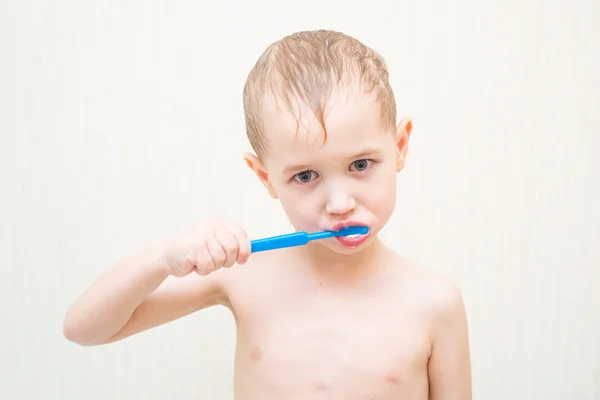 Blonde beautiful boy brushing his teeth in the bathroom — Stock Photo, Image