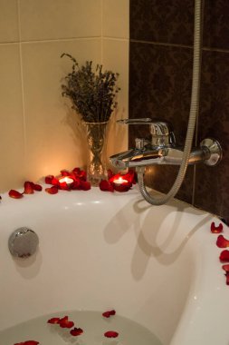 Banyoda aromatik mumlar ve gül yapraklarıyla rahatla. Spa zamanı..