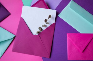 Renkli bir arkaplanda boş bir notla pembe zarf..