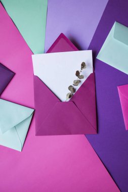 Renkli bir arkaplanda boş bir notla pembe zarf..