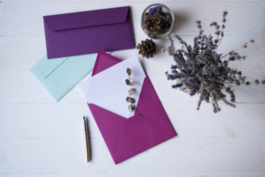 Beyaz ahşap masanın üzerinde boş bir not olan pembe zarf. Güzel masaüstü. Metin için yeri olan arkaplan.