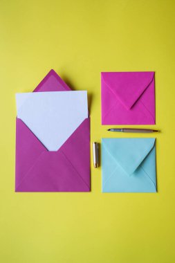 Sarı arkaplanda boş notlar olan renkli zarflar. Kopyalama alanı olan arkaplan.