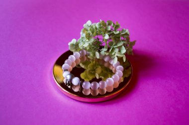 Pembe arka planda dekor olan el bilekliği..