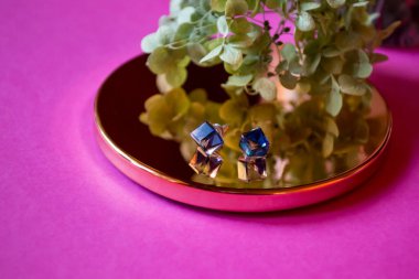 Pembe arka planda süsleri olan küpeler..