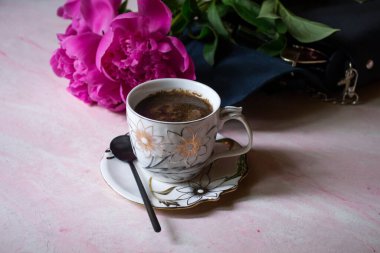 Bir fincan kahve, şakayık ve kadın çantası..