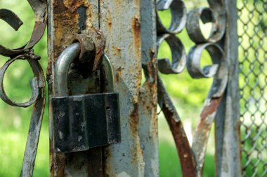 Paslı bir çitin üzerindeki eski asma kilit..