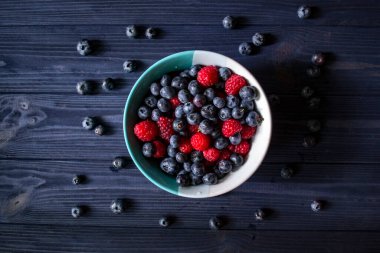 Masada yabanmersini ve ahududu olan kase. Çilek karışımı..