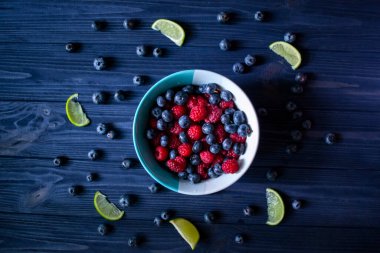 Masada yabanmersini ve ahududu olan kase. Çilek karışımı..