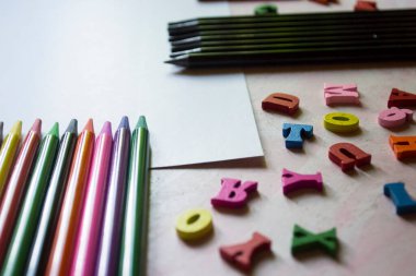 Masanın üzerinde çok renkli harfler ve kalemler var. Masadaki renkli tahta alfabe ve kalemler..