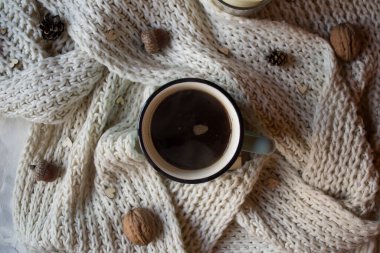 Bir fincan kahve ve masasında süslemeler olan yün eşarp. Sıcaklık.