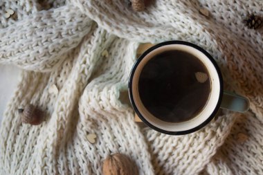 Bir fincan kahve ve masasında süslemeler olan yün eşarp. Sıcaklık.