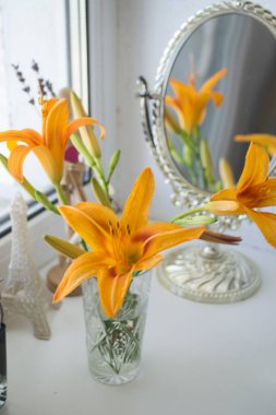 Aynanın yanındaki turuncu zambak. Çiçekler ve ayna yansıması.