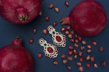 Soutache Bijuteri küpe kırmızı taşlar ve koyu mavi arka plan karşı nar