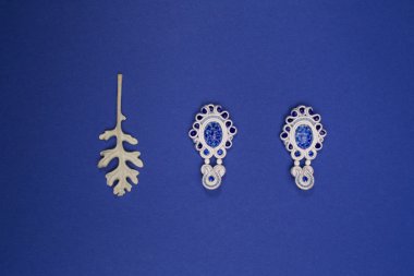 Soutache beyaz Bijuteri küpe mavi taşlar ve kristaller beyaz yaprak ile mavi arka plan üzerinde