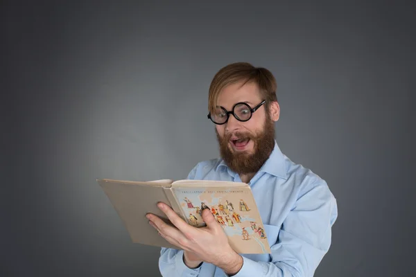 Jovem barbudo vestindo óculos lendo um livro Fotos De Bancos De Imagens Sem Royalties