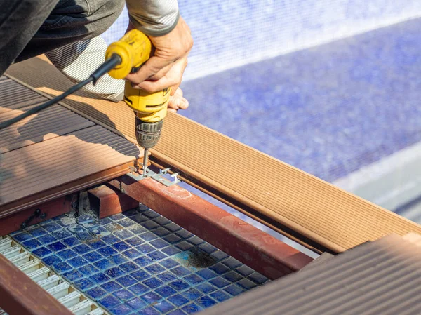 Man assembling composite deck using cordless screwdriver.