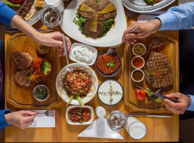 Farklı restoran yemekleri ve elleri olan güzel servis edilmiş bir masa.