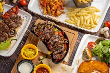 Et fajita, köfte, tavuk şnitzel ve ahşap masada köri soslu tavuk.