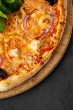 Koyu gri taş masada lezzetli deniz ürünleri pizzası.