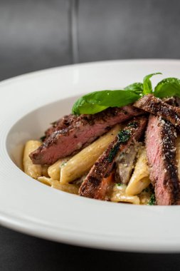 Dilimlenmiş et ve kremalı makarna.