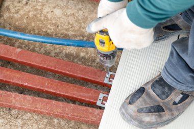 Kablosuz tornavida kullanarak kompozit güverte oluşturan adam.