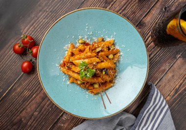 Domates soslu makarna, ahşap arka planda maydanozla süslenmiş domates.