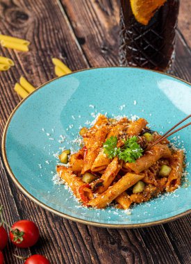 Domates soslu makarna, ahşap arka planda maydanozla süslenmiş domates.