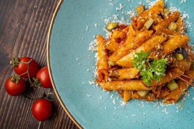 Domates soslu makarna, ahşap arka planda maydanozla süslenmiş domates.